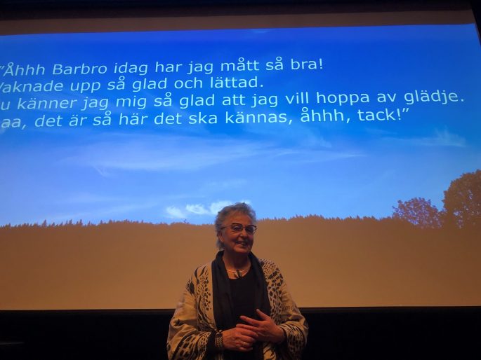 Barbro har grått korthår, glasögon och håller ett anförande