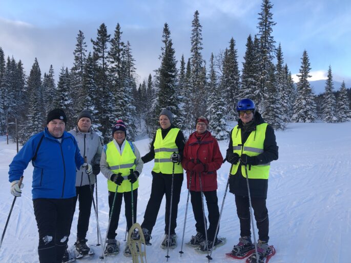 Gänget står uppradade i snöskor. En del har gula västar på sig. Lisa håller upp ena snöskon.