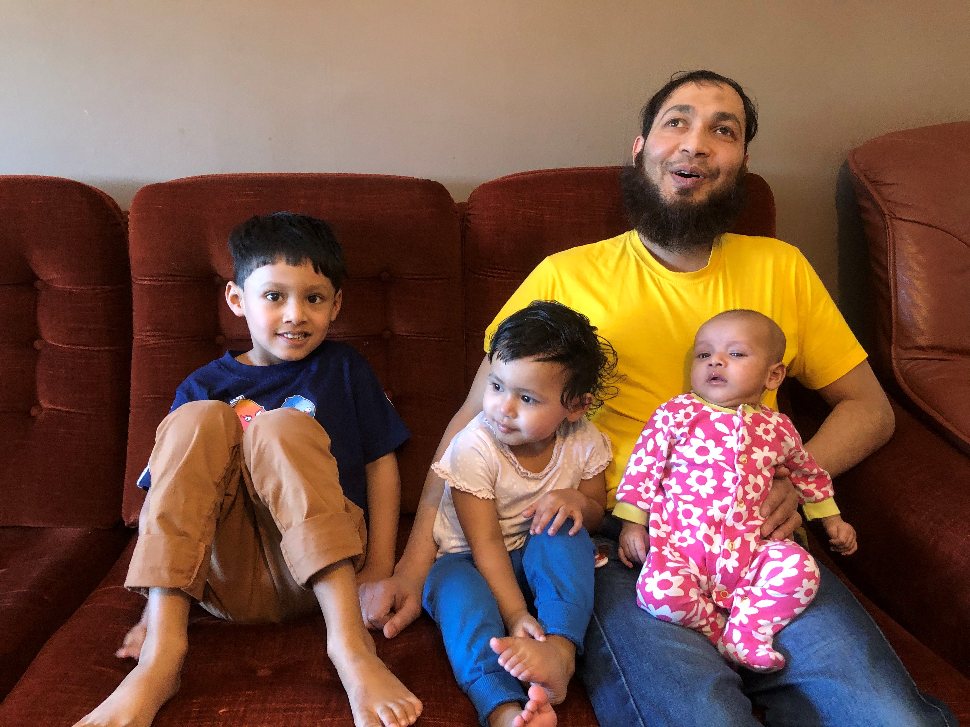 Amanullah sitter i soffan med sina tre små barn.