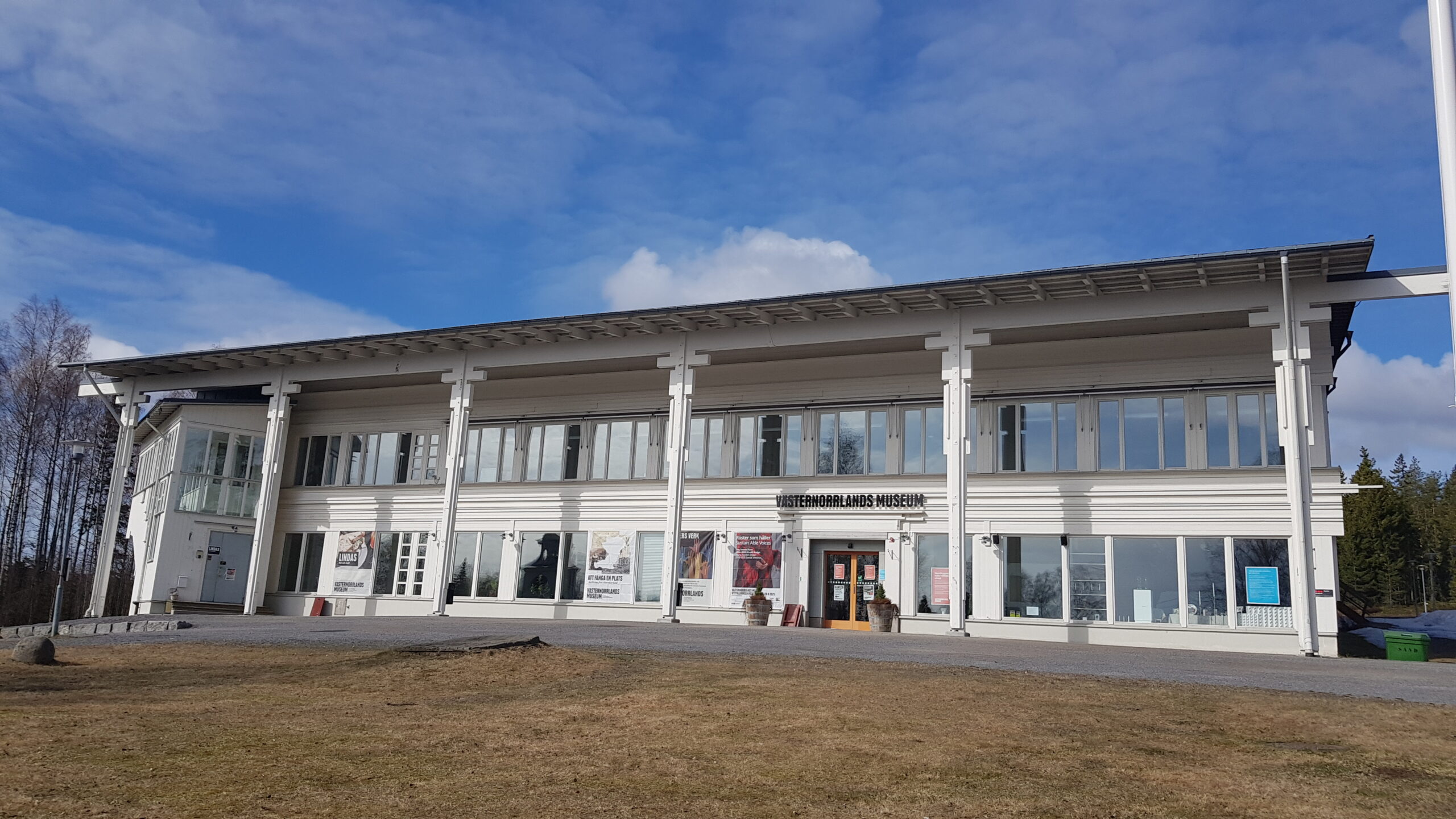 Framsidan av Västernorrlands museum en vårdag med blå himmel och brunt gräs