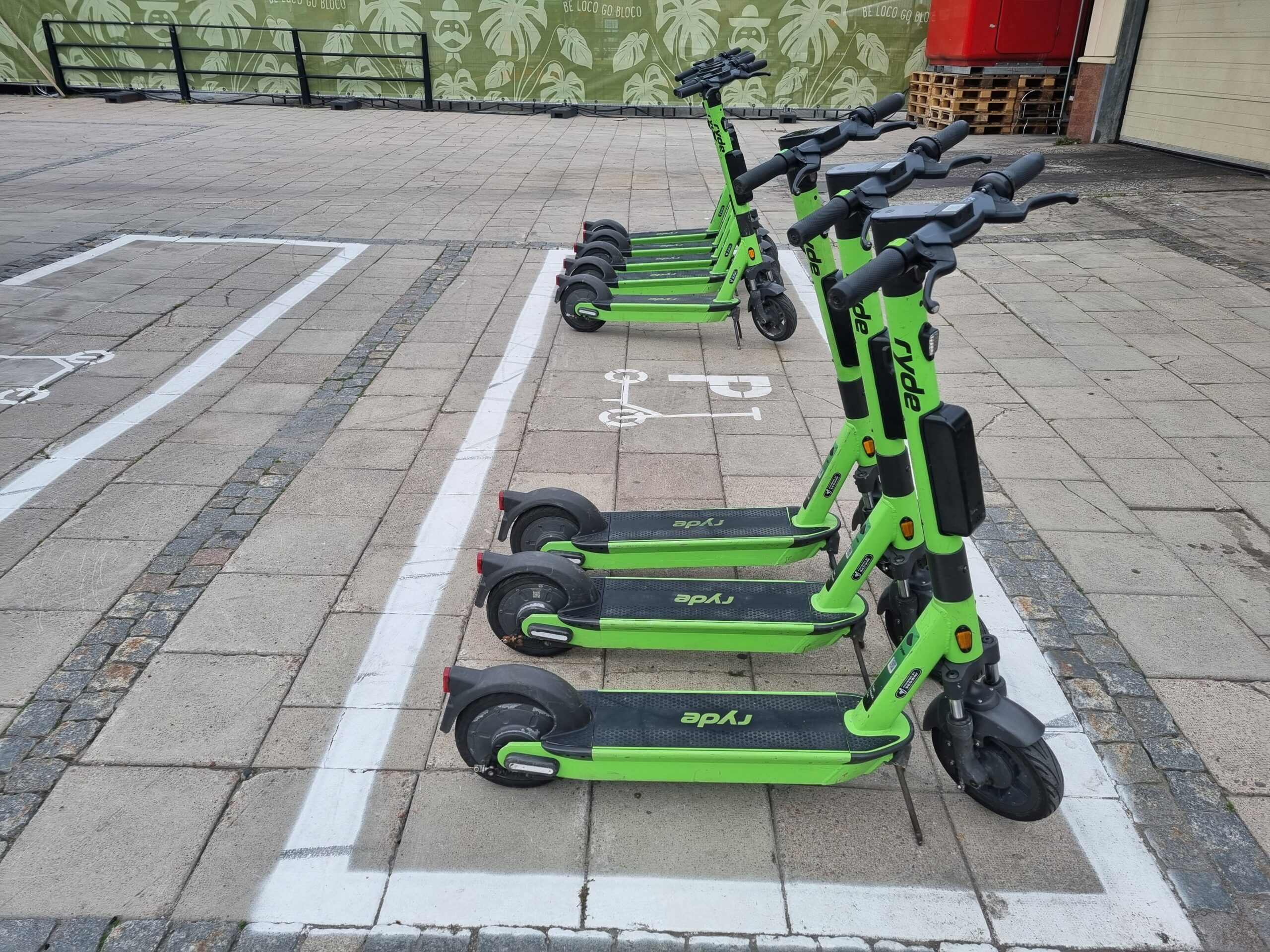 Ett gäng gröna elsparkcyklar ståendes på en hänvisad parkeringsruta